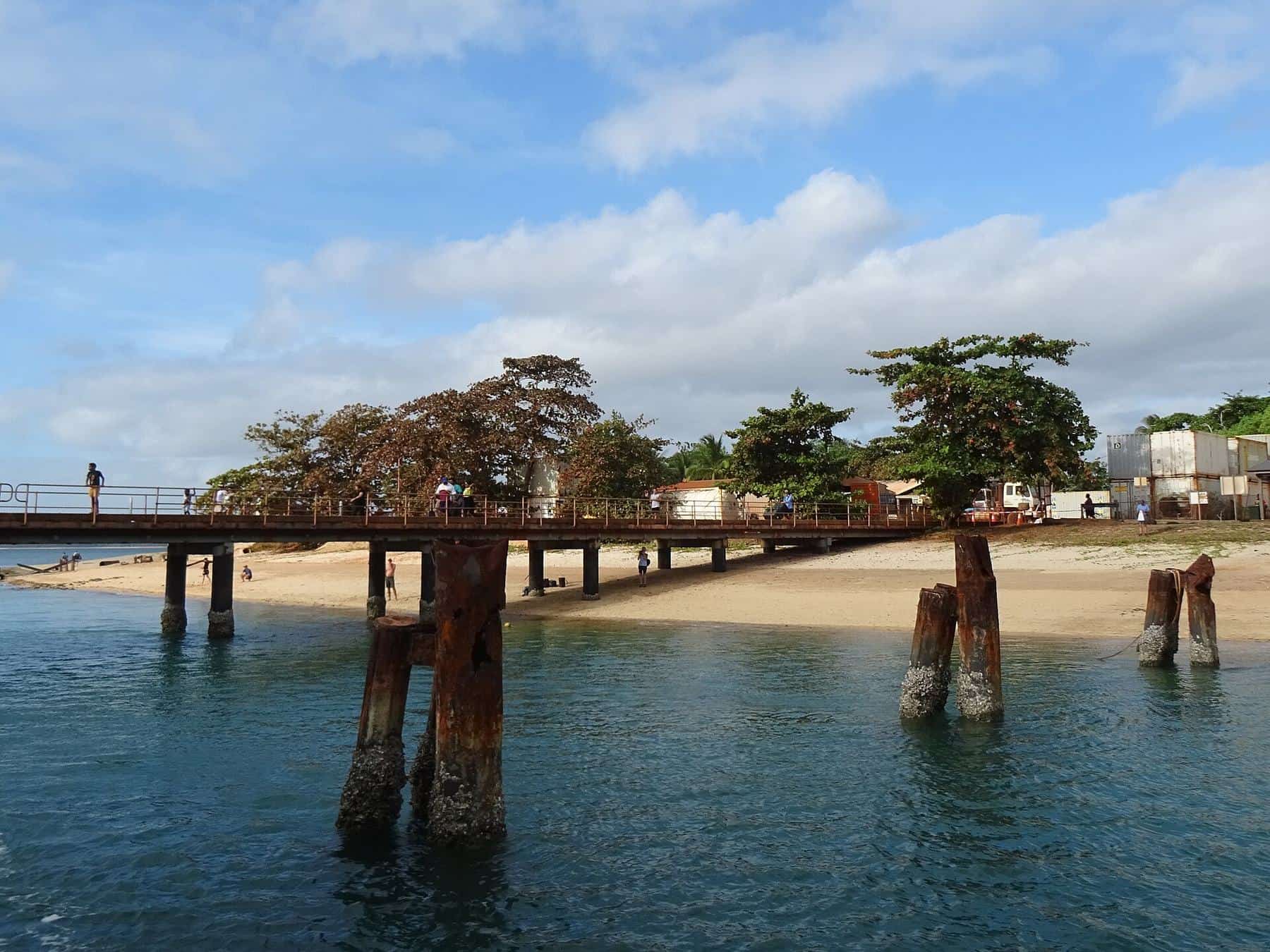 A weathered timber jetty extending into clear turquoise water at Seisia under a blue sky