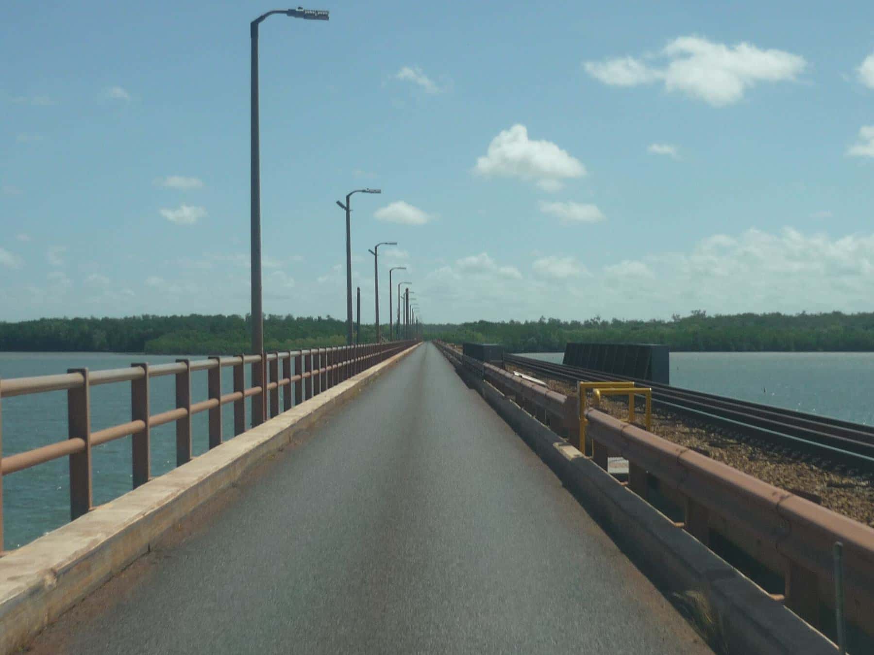 A long, straight concrete bridge with lamp posts crossing the Mission River near Weipa